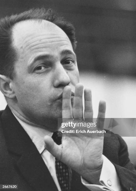 French composer and conductor Pierre Boulez shushing the orchestra with his hand.