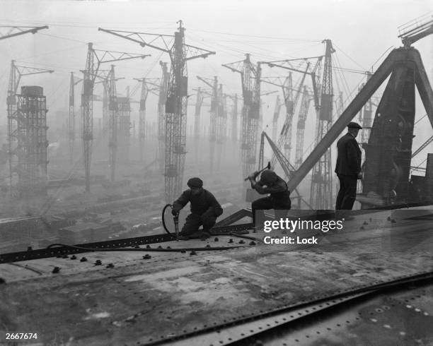 Riveters at work on the top deck of the new Cunard White Star liner Queen Mary, under construction at the John Brown & Co shipyard, Clydebank.