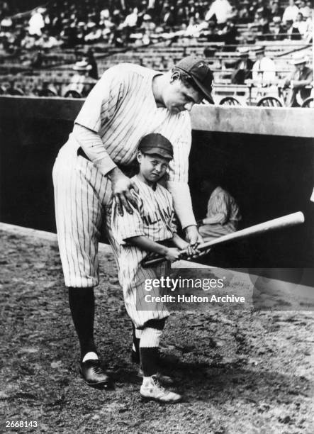 George Herman Ruth known as 'Babe' Ruth, American baseball player, showing a youngster how to hold a basesball bat in Yankee Stadium.