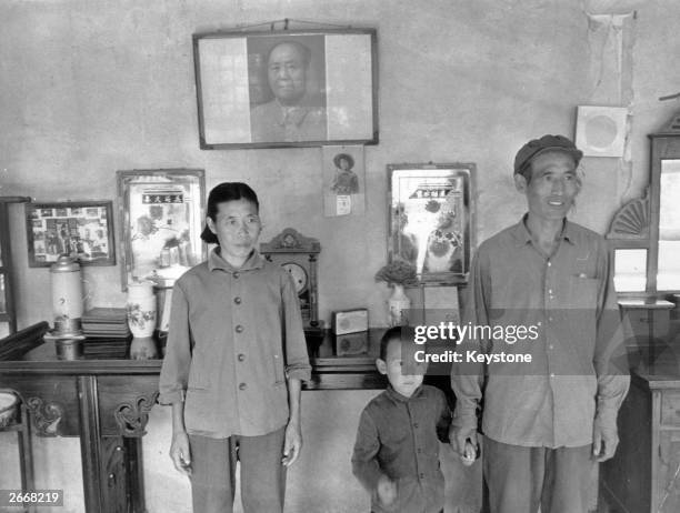 Chinese family in front of a framed portrait of the Communist leader Mao Tse-Tung.