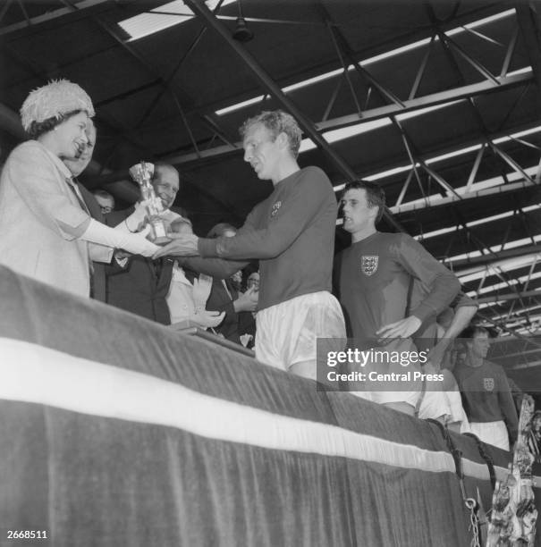 Queen Elizabeth II of Great Britain presenting the World Cup to the England captain, Bobby Moore, while the Duke of Edinburgh looks on. Geoff Hurst,...