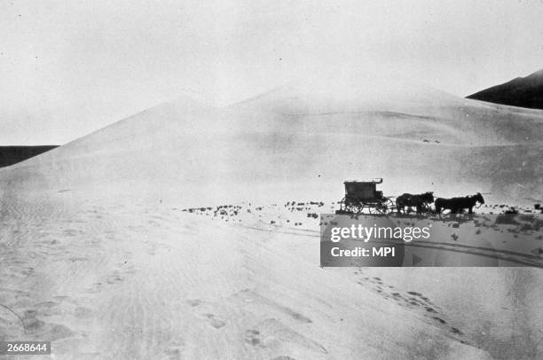 Covered wagon makes its way across the Carson Desert, Nevada. This is the mobile darkroom of Timothy O’Sullivan, as official photographer during the...