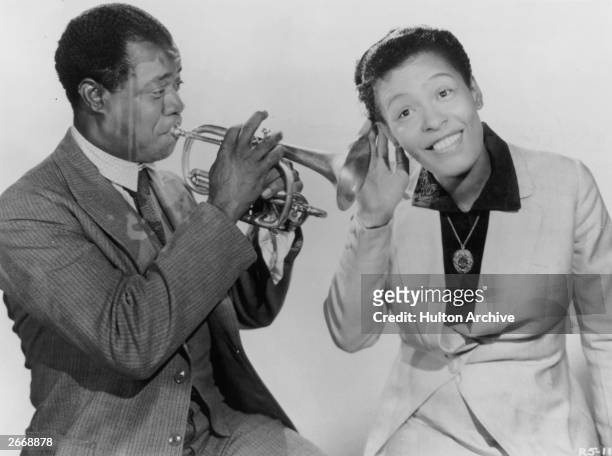 Billie Holiday pays close attention to Louis Armstrong . They are both appearing in the film, 'New Orleans' directed by Arthur Lubin.
