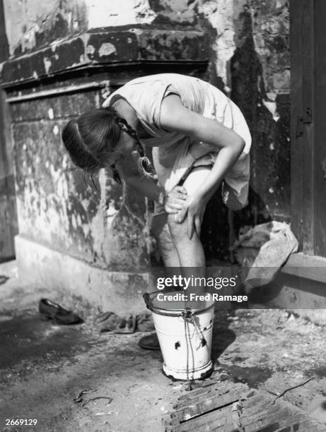Young German evacuee returning to Berlin washes her feet in a bucket on the roadside.