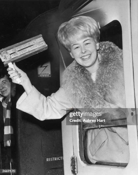 Christine McCann, finacee of Chelsea FC captain Terry Venables, leans out of a carriage window waving a rattle as she leaves Paddington station on a...