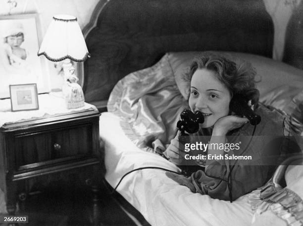 German-born actress and singer Marlene Dietrich making a telephone call to her daughter from her bed in Hollywood.