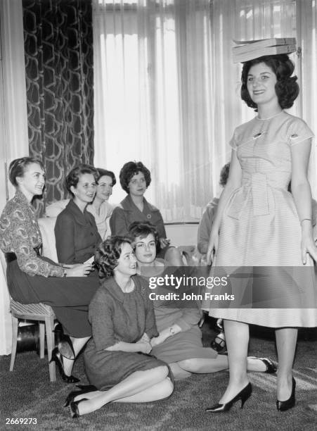 Year old Virginia Lyon practices her deportment by balancing telephone directories on her head, watched by other debutantes selected to model in the...