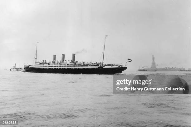The Hamburg America liner Kaiserin Augusta Victoria sails past the Statue of Liberty in New York Harbour.
