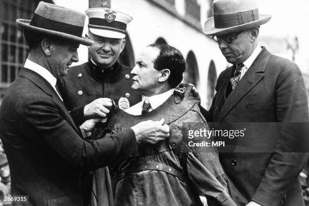 Hungarian born magician and escapologist Harry Houdini being fitted into an escape proof suit.