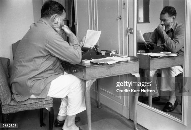 Pyjama clad author and journalist Ernest Miller Hemingway writes up copy for a report on World War II in Europe. Hemingway is a war reporter and...