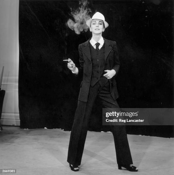 Model strikes a masculine look wearing a pinstriped trouser suit by Yves Saint Laurent, 23rd February 1967. His plainer suit for evening wear known...