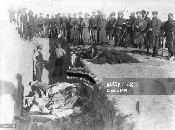 Bodies of Sioux Indians being unceremoniously piled into a mass grave hacked into the frozen Dakota soil after the tragedy at Wounded Knee, South...