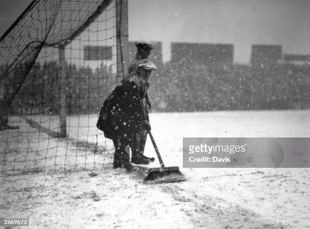 Groundsman sweeps snow away from the goal line at Craven Cottage, London, before a FA Cup tie replay between Fulham and Everton.