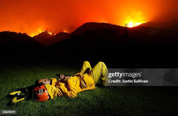 Los Angeles County Fire Captain David Martinez takes a nap as a wildfire approaches October 27, 2003 in Chatsworth, California. Wildfires continue to...