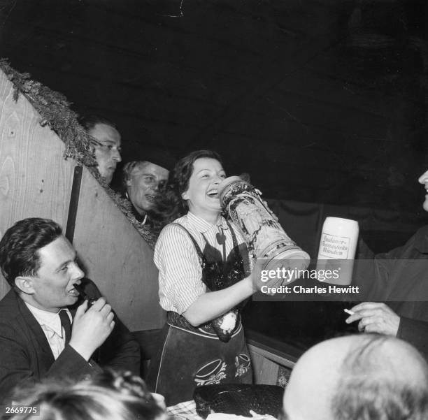 Woman holding up a German beer mug at the Oktoberfest beer festival in Munich. Original Publication: Picture Post - 5805 - Munich Beer Festival -...