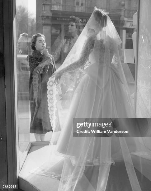 Young woman, Georgina Franklin, looking at a wedding dress in the window of the Bridal Boutique in Putney, south-west London. It is the first shop in...