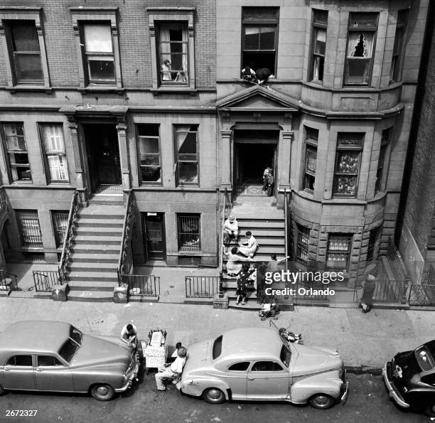Puerto Rican immigrants congregate on the steps and in the street, outside their tenement blocks in the poorest areas of New York.