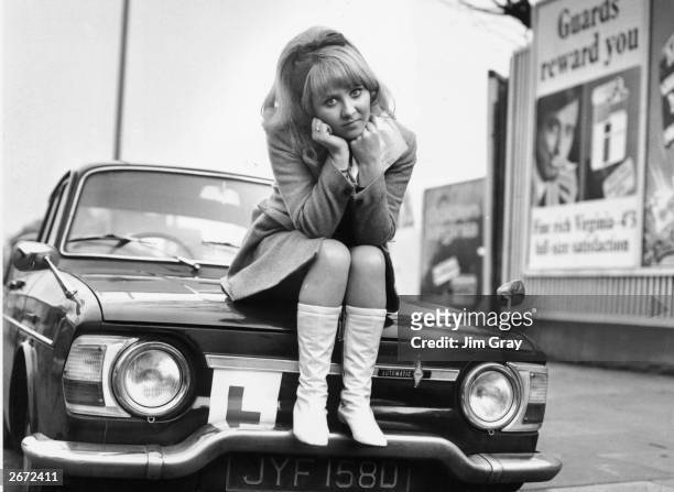 British pop singer Lulu sits on the bonnet of her car looking disappointed after failing her driving test at Isleworth.