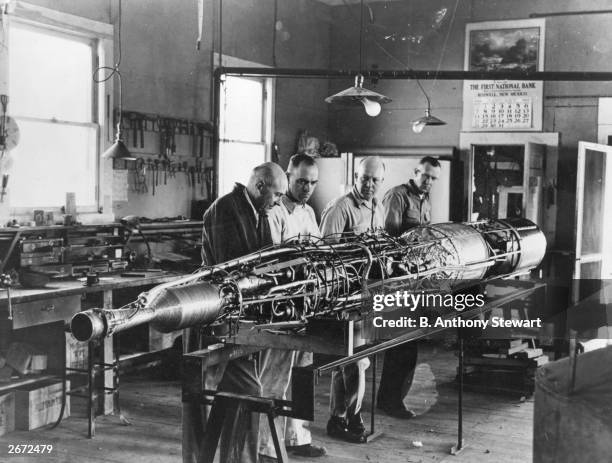 Rocket pioneer Dr Robert Hutchings Goddard on the left, and three colleagues working on a rocket with the casing removed.