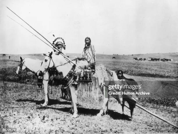 Blackfoot chief and squaw.' The family is traveling on horseback carrying a child on a travois.