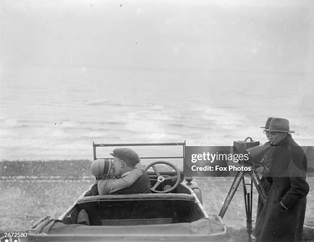 Couple in an open car locked in a passionate embrace for a scene in the film, The Thrill, being shot on Brighton beach.