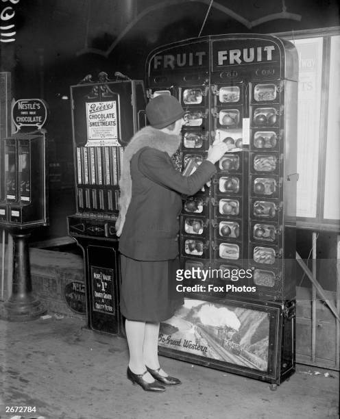 Woman buys some fruit from a coin-operated vending machine at Paddington Station, London.