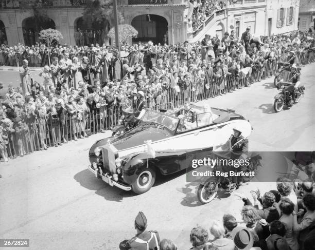 American actress Grace Kelly and Prince Rainier III of Monaco drive through the streets in their Rolls Royce car after their wedding ceremony at...