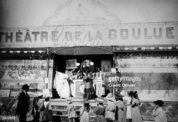 La Goulue's theatre In Paris. She was a can-can dancer from the Moulin Rouge. Some of the performers on the steps of the theatre are drawing a crowd.