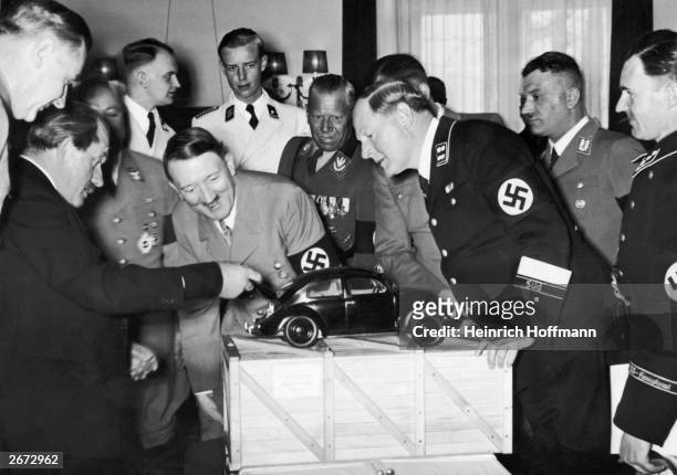 Nazi leader Adolf Hitler admires a model of the Volkswagen car and is amused to find the engine in the boot. He is with the designer Ferdinand...
