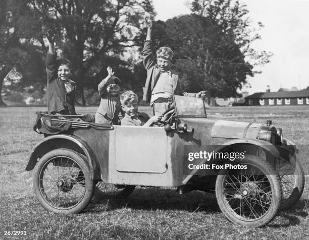 Two young boys drive their friends round a field in an Austin Seven car from their father's garage in Titchmarsh, Kettering.