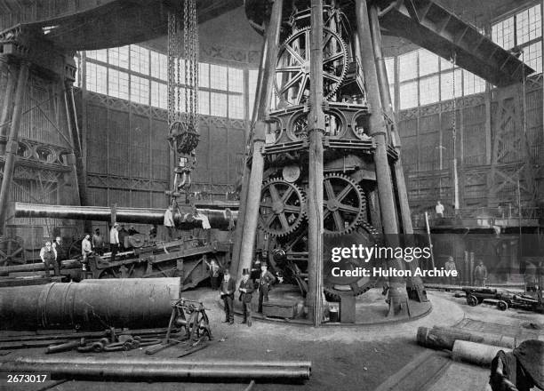 Heavy breech-loading gun being lowered into its place on its carriage by a powerful steam crane at the Arsenal in Woolwich.