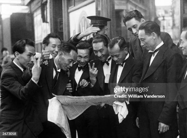 Group of delighted Chinese waiters read about Japan's surrender in a newspaper in London's West End.