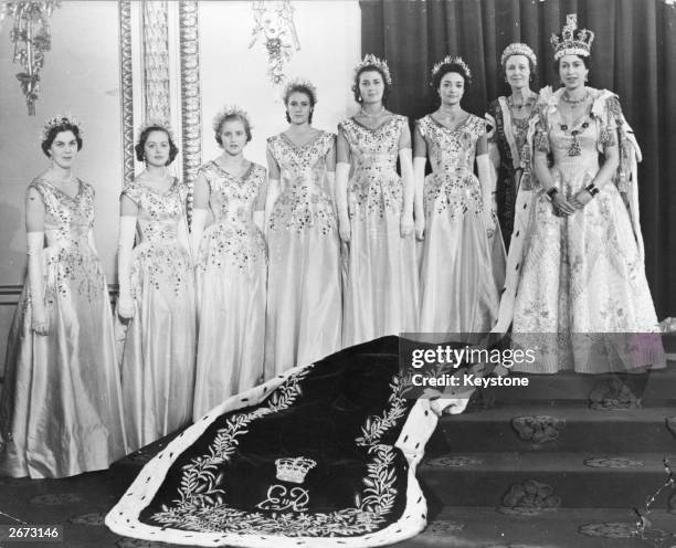 Queen Elizabeth II wearing robes of state in the Throne Room at Buckingham Palace, London, on her coronation day. Her Maids of Honour are beside her:...