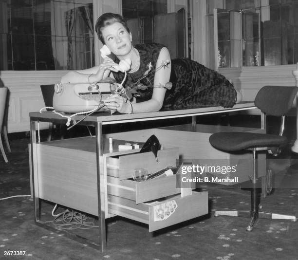 Actress Lois Maxwell who plays Miss Moneypenny in the Bond films drapes herself across a desk designed by Intra Design Ltd a company set up by the...