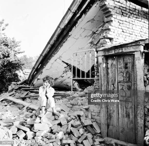 Young girl sits on the rubble of her home which was destroyed during the Skopje earthquake, Yugoslavia.