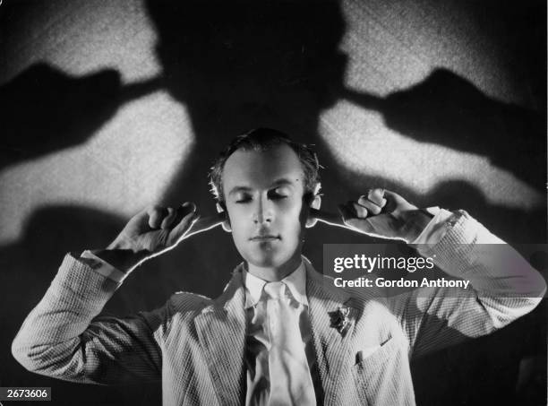 British photographer and designer Cecil Beaton blocks his ears, circa 1930.