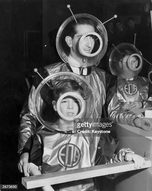 Former King Peter of Yugoslavia and his son Prince Alexander wearing space suits as they prepare to enter the 'Space Machine' at the Schoolboys' Own...