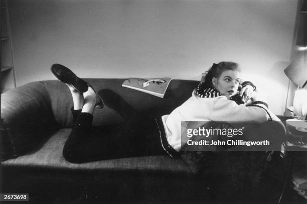 Model Miss G Ashley sprawls on a sofa as she models a 5 guinea sweater from Kenettas, Baker Street, London. The sweater has a yoke with a radiating...