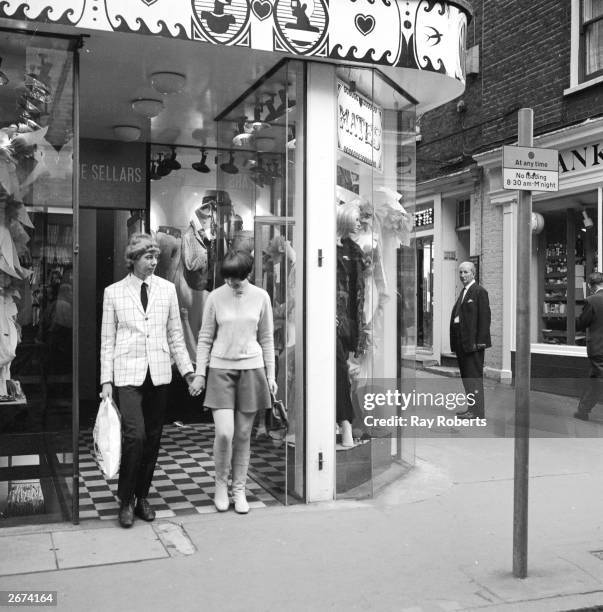 Young couple coming out of Mates boutique in Carnaby Street, London. The shop is unique in selling both men's and women's clothing.
