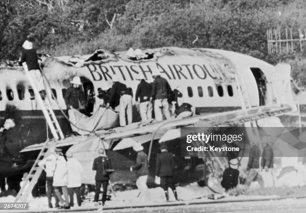 Firemen examining the wreckage of a British Airtours Boeing 747 which burst into flames during take off at Manchester Airport, killing 54...