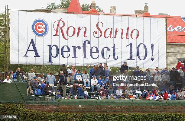 Fans of the Chicago Cubs watch the game in front of a sign honoring longtime Cubs third baseman and current WGN Radio color commentator Ron Santo...