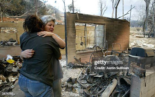 Lorraine Messmer hugs her daughter Tessa as they stand in their burnt out home October 28, 2003 in Waterman Canyon, California. Wildfires continue to...