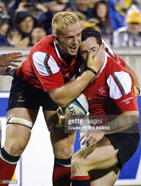 Welsh scrumhalf Gareth Cooper is congratulated by teammate Alix Popham after scoring the first try in the Pool D Rugby World Cup 2003 game between...