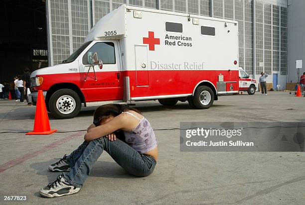 Jaylene Smith of Crestline, California rests in front of an American Red Cross truck at an evacuation at the San Bernardino Airport shelter October...