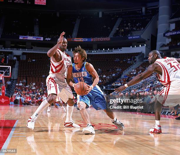 Yuta Tabuse of the Denver Nuggets drives the ball against Moochie Norris the Houston Rockets during the NBA preseason game at Toyota Center on...