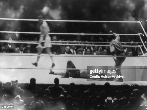 Argentine heavyweight champion Luis Angel Firpo lies knocked out by American world heavyweight champion boxer Jack Dempsey at the end of their match...