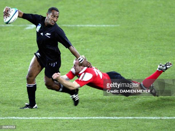 New Zealand winger Joe Rokocoko evades a tackle by Welsh winger Gareth Thomas to scores the second try during their final Pool D Rugby World Cup 2003...