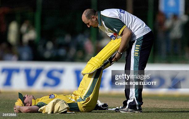 Australian cricketer Michael Clarke gets treatment from an unidentified trainer for a pulled leg muscle during the TVS tri-series one day...