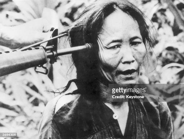 Vietnamese civilian with a gun pointed at the side of her head.