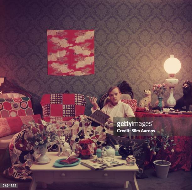 Premium Rates Apply. Author Truman Capote relaxes with a book and a cigarette in his cluttered apartment, Brooklyn Heights, New York. Original...